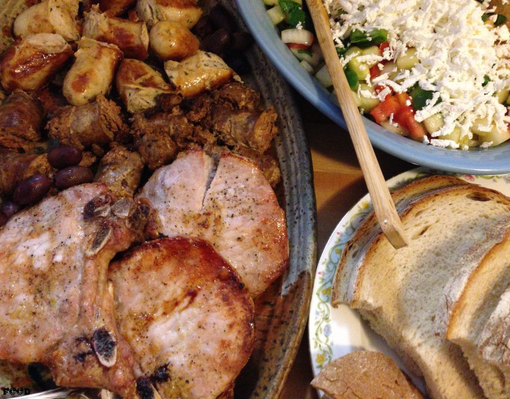 clockwise from top, sausage, sausage, pork chops, bread, cucumber tomato salad