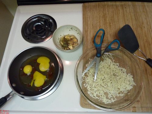 eggs in frying pan, where they should be, mushrooms, broken up, dried, in a dish of water, and a clear pie pan filled with cheese, back when this was made, I liked eating out of clear pie pans, nice and big, hold plenty of food