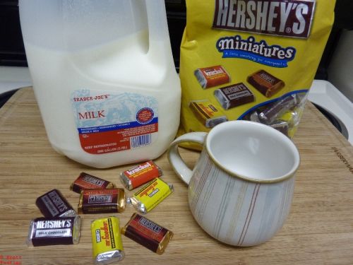 Hot Chocolate ingredients list, milk, hersheys minatures, mug, eight random pieces artfully displayed on a cutting board for maximum photogenetic effect
