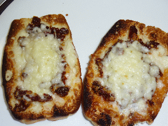 Pizza bread, nice and brown, very well cooked, if I do say so myself, two pieces, lots of cheese, looks devine, what about it looks so good, well, I am hungry now as I write, been at this awhile, sweet hawaiian bread, cheese, maybe sun dried tomatoes, yeah, caption agrees, and those pack a lot of flavor, probably no sauce at all, just the oil and spices from the dried tomatoes