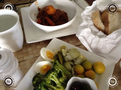 now, this is a nice place setting, looks to be root vegetables in bowl, bread, kumquates eggs, broccoli, olives, and artichoke hearts on plate