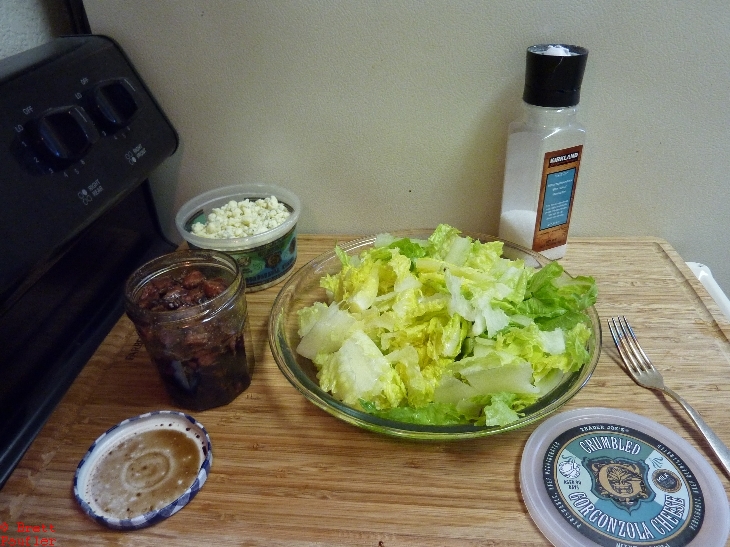 Glass of dressing, container of blue cheese, load of lettuce, this would be a meal for one, all you can eat salad, probably pretty healthy considering what I am eating now, not nearly as much salad
