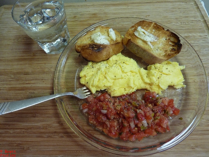 Pie plate on wood cutting board, silver fork, nice and long, short glass of ice water, even after all these years, that toast looks marvelous, i was great at making toast, eggs and helping of salsa, so breakfast