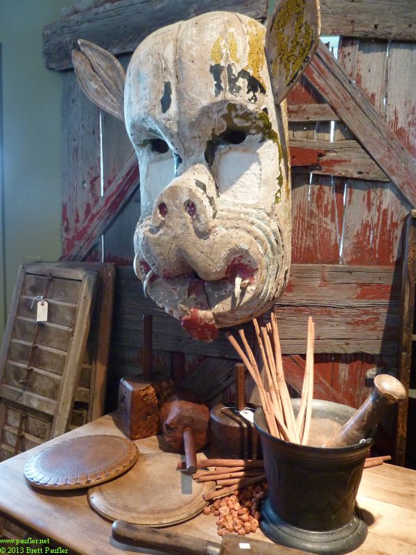 Wooden pig head like totem pole mask mounted to wall, working tools below, nice wood work, nice old time look