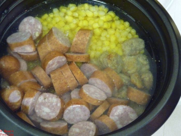 cold pot full of ingredients, eccentially prepping a crock cooker and letting it go, corn, sausage, rice unseen, all covered in water