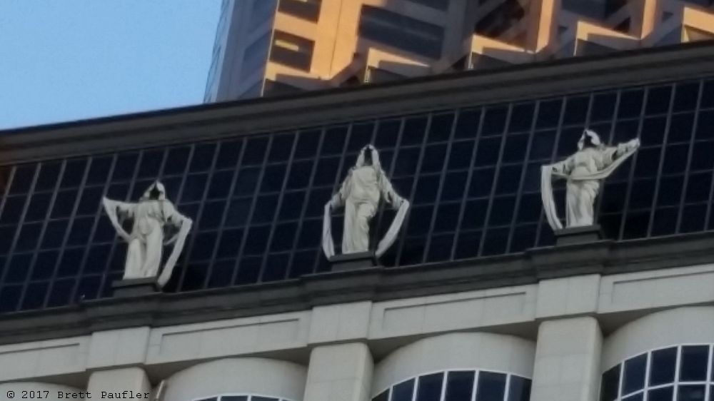 Statues of ghosts or spirits, downtown SF, Union Square ways, towards Chinatown, three on each side of the building up top, close up view, one can be in a place for a long time before they notice such things, or be walking down the road for the first time