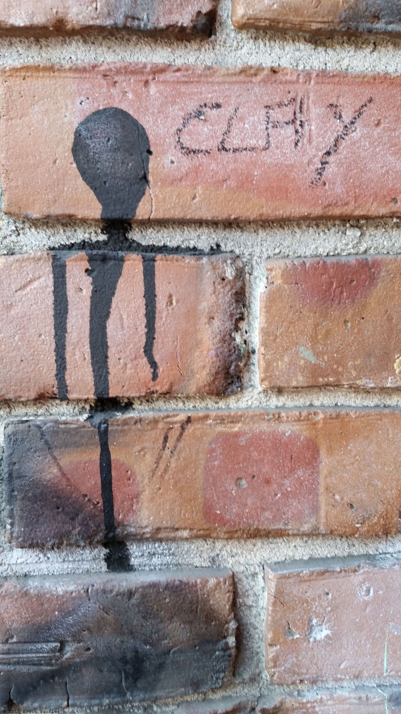 Brick wall with paint splotch I like to think looks sort of man or alien like with the word clay next to it, so Clay, my previous slippery handed friend, was clearly an alien, and therefore, killing him was a matter of global defense, and or, it looks like something vaguely human, which is what the cops said when they showed up, ironically enough