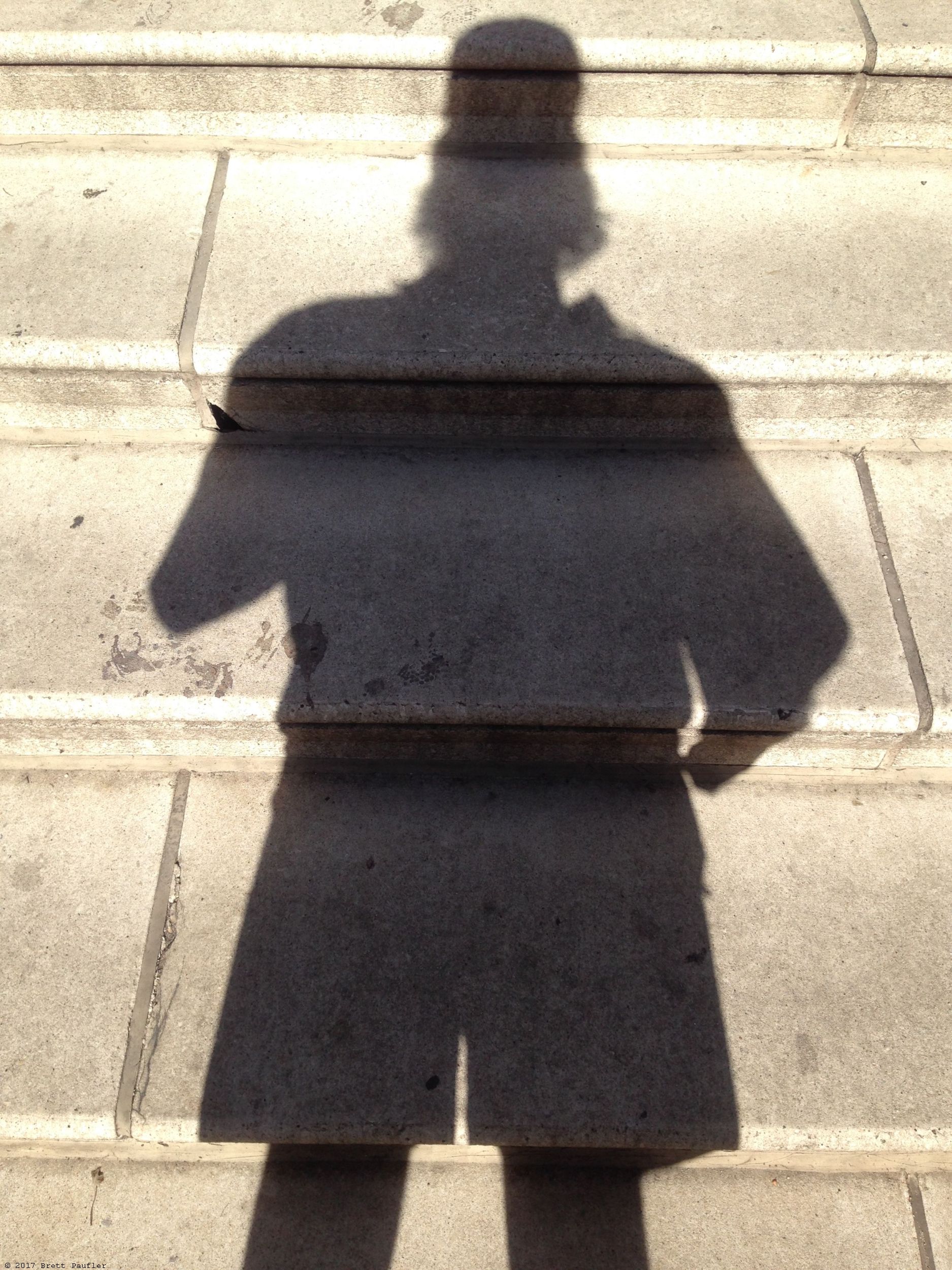 Self Portrait, shadow on steps in urban jungle setting, artist wears a baseball cap, hawaii shirt, and dorky shorts, none of which is really noticable, as it is an image of a shadow, mine, on some nice steps, and like everything else on the page, I just sort of like the way they look, so art, and the metaphorical meanings they hold, way to deep and sublime for the likes of you to understand, seriously is that pigeon shit or spit by my head, well if you could read the image, you would not have to ask, also note how the image is a bit brighter around my noggin, that is called a halo, it is sourced by god... or the sun... or whatever, I have said too much