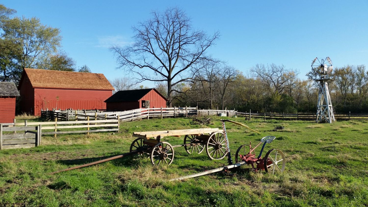 Same preserve, this is the farm area, a nice little walk, there were cows and pigs here, but none shown, a field in a farm, barns in the background, wagon and plow in the foreground, windmill to the side, green grass, early fall