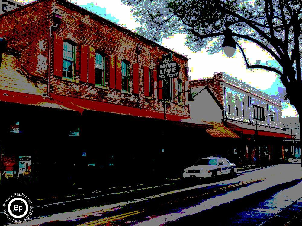 just a street, the sign, I'm pretty sure it old, really old, almost a historic marker at this point, says something about naked dancers, below it a police car, not much else on the street