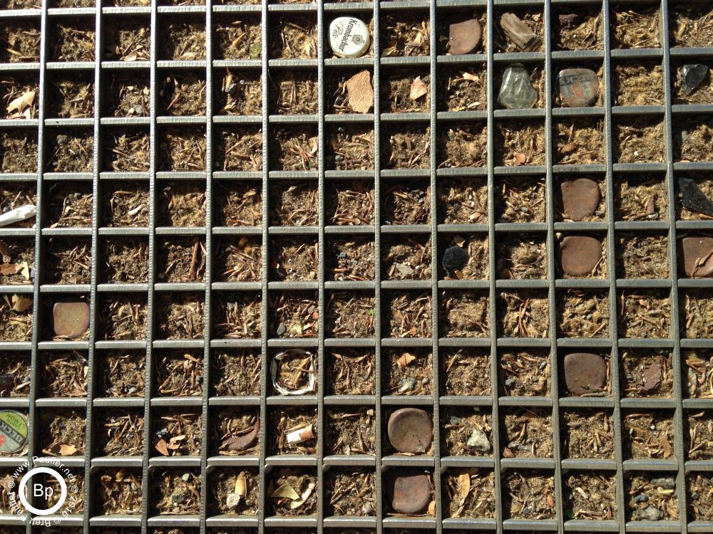 Coke bottle tops, and beer bottle tops, stuck into a grate, on the ground, it was one of those tree grates, used to protect a trees roots, that is landscaping bark in between, and a few of the grate areas have bottle tops, again, artsy image, knew it was a winner when I took it
