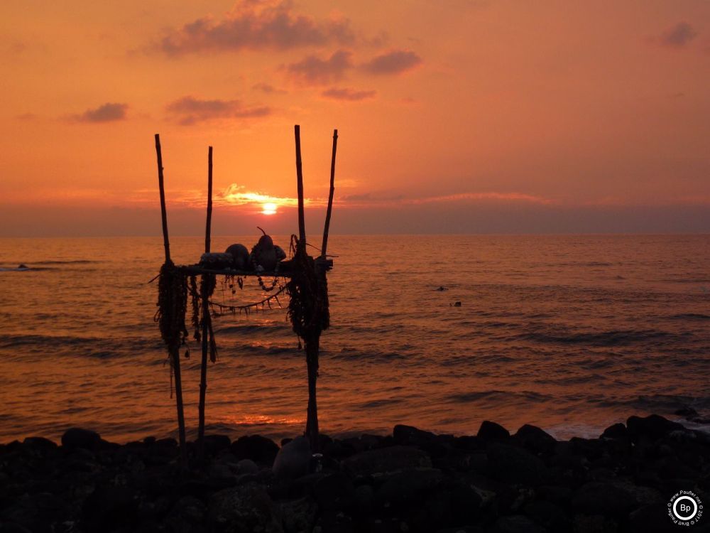 This would be an altar like thing down by the sea in Hawaii, Heiau, I believe is what it is called, on the platform where offerings as might be befiting a god or certainly what those who placed them there considered important, intoxicants, money, flowers, and behind it all, the setting sun, quite the photograph in my ever so humble opinion