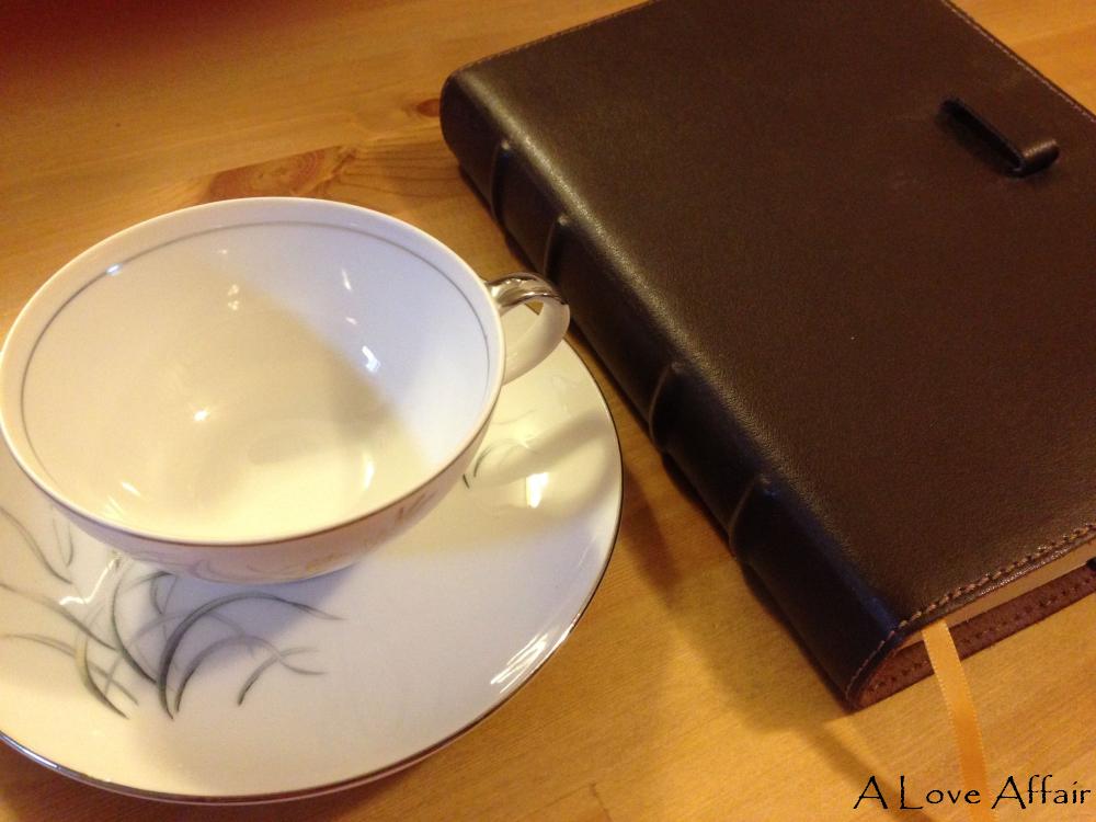 Cup and Saucer.  The Cup is Already Broken.  And the same book, journal, leather bound grouping of paper is present.  They make a good team.