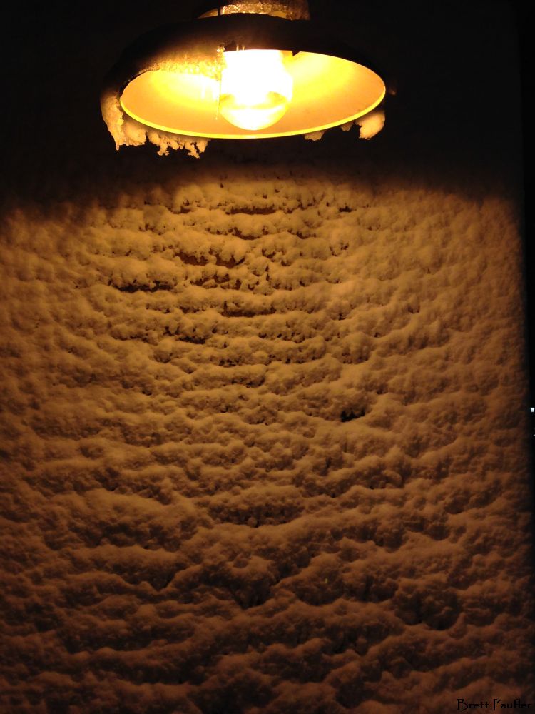 snow covered brick wall under a light