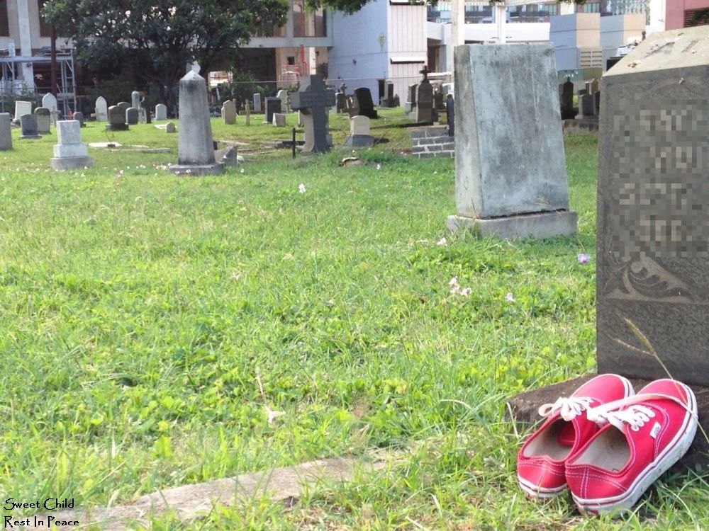 a pair of pink gym shoes resting by a headstone in a cemetary, I collected this image long ago intending to add it to the Lilikoi Walk Project, I forget what I call that, ok, I looked it up, It is Gilding The Lily, but it has been years and years, time to use this picture up