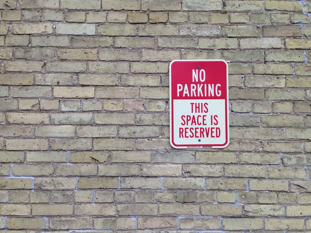 No Parking, No Standing, No Sitting, No Reading, This Means You! a No Parking sign attached to a grey brick wall, the image is more about the grey bricks, pleasing to look at, than the sign, as the sign is totally out of context, even if it is the sign that calls to the text, below