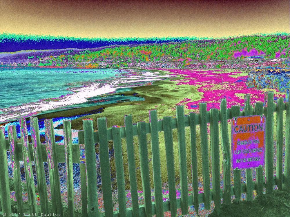 The beach in full bloom, algae bloom, some toxic spill, or likely as not, some other filter, given the greenish sand a pinkish hue, the further away, all behind a wood fence, caution, something about falling off the cliff, better grab hold of what little reality is left