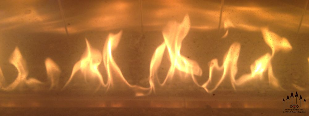 Flames from a gas light effect, one of those ambient rolling flame effects, from the entrance to a restaurant, the flame behind double walled glass