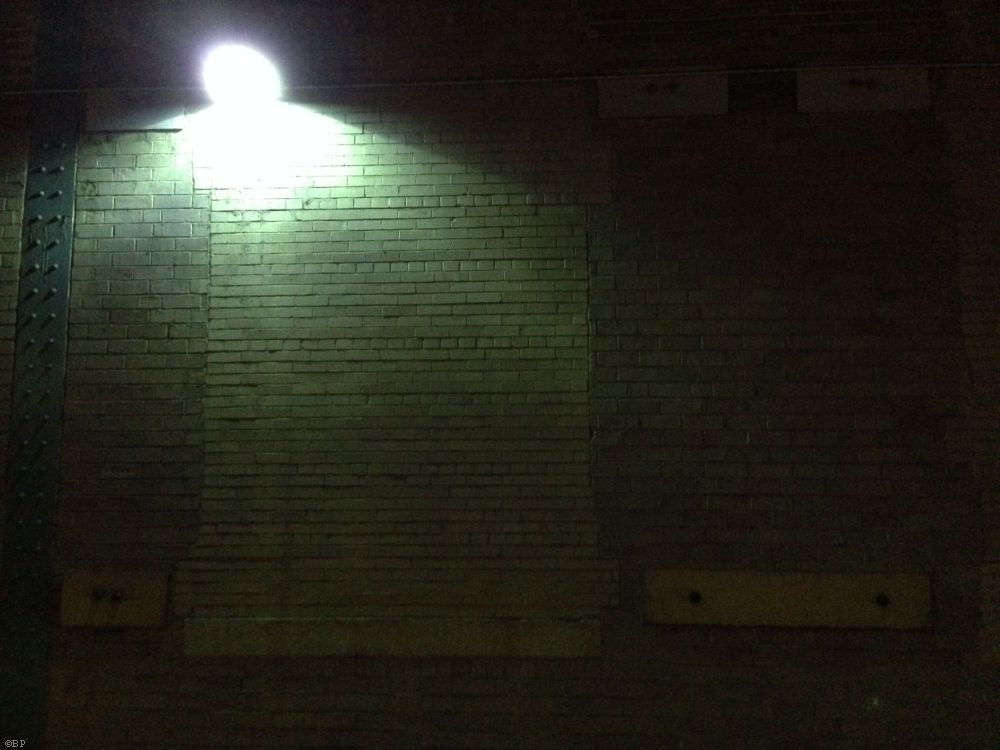 Train Station Interior Over Tracks, showing an overhead light illuminating a brick wall, I like the green tones