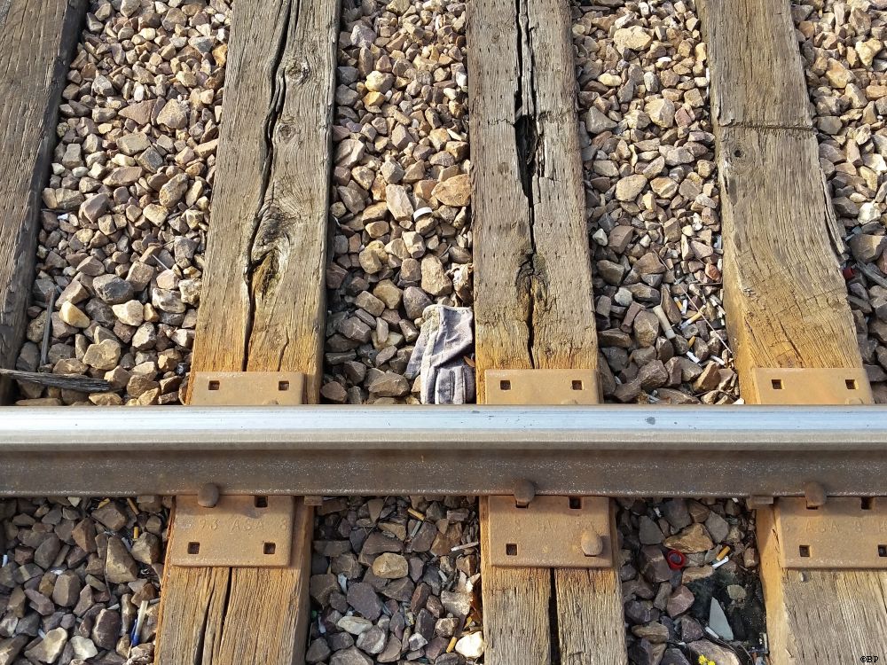 Train Track with a glove nestled between the cross wooden supports, a simple close up detail of tracks