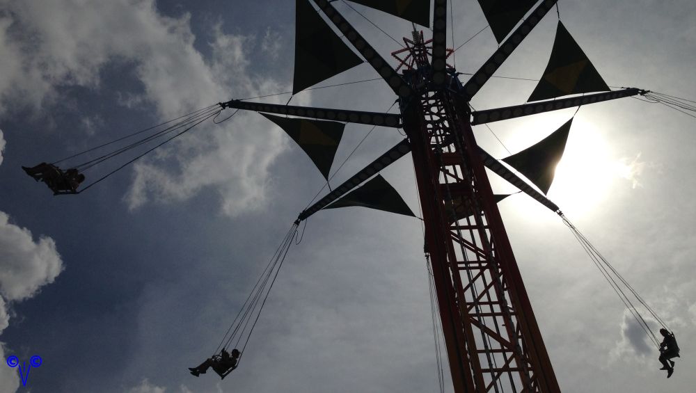 This would be a picture of that swing ride, were you sit in a seemingly harmless swing set harness at ground level and then they raise the thing up like a thousand feet in the sky and they whip you -- not me, not by a long shot -- they whip you around and around until you feel like puking and stop caring if you fall out of the blessed thing or not, also, clouds in the background, as this was a few minutes before they shut the part down, and maybe a few minutes, call it rides, after the manager started walking around telling everyone to shut it down, which they will, just as soon as the paying customers get the hint and leave, oh, and talk about a lighting rod, you do not want to be on that thing when lightning hits, me, I just do not want to be on that thing