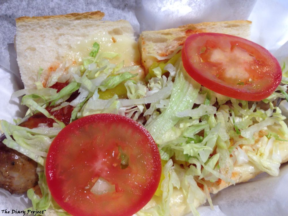 Italian Sausage sandwich drizzled with red sauce, lettuce, and tomatoes