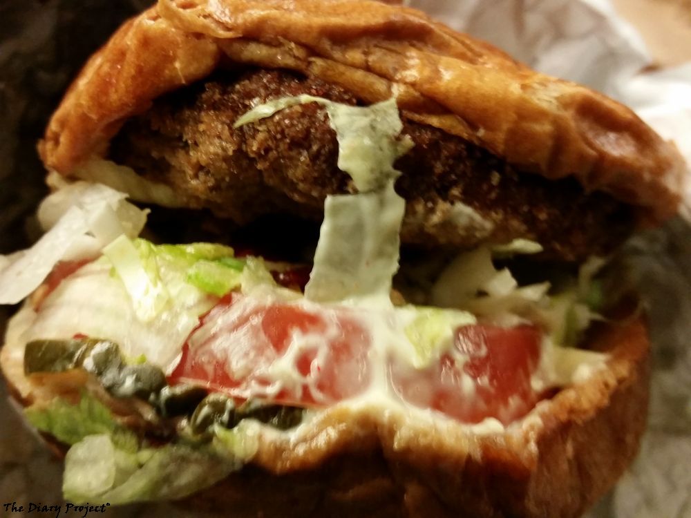 A pork sandwich, the picture here is taken on the train on the way back, being the second sandwich, it is a hamburger, basically, with a fried pork patty, loaded with lettuce, tomatoes, mayonnaise and pickles, maybe other stuff