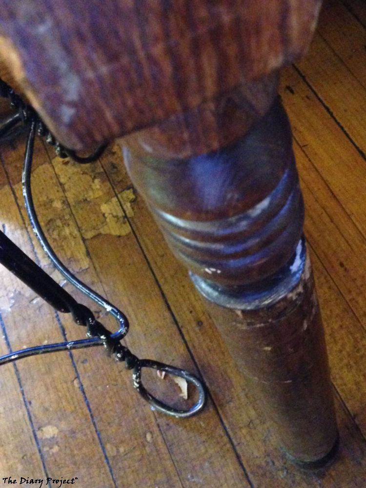 A table leg, nice and weathered, wire frame chair leg to the side, with water stained wood floor in background, runners up for the image on this outing included an image of their butterfly bird bath and before and after images of the banana split, but that is sort of boring, so a table leg, it is
