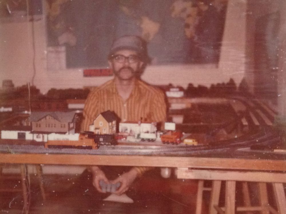 So, my dad posing with his train set, maybe I mentioned we had a large basement, full size, went the complete length under a four bedroom ranch style house, so reasonably large, and this was located in a nook, under the stairs, two pieces of 4x8 plywood with a 4x4 hole cut in the center, so wrap around trains, lots of trains, buildings he made, guess he liked models, its easy to picture him in the basement, large basement, large enough to cordon off a area for an office den and in there he would put on his old war movies, spend Saturday working on a model or something, we would join him, or not, mostly not, but enough to know what he was about