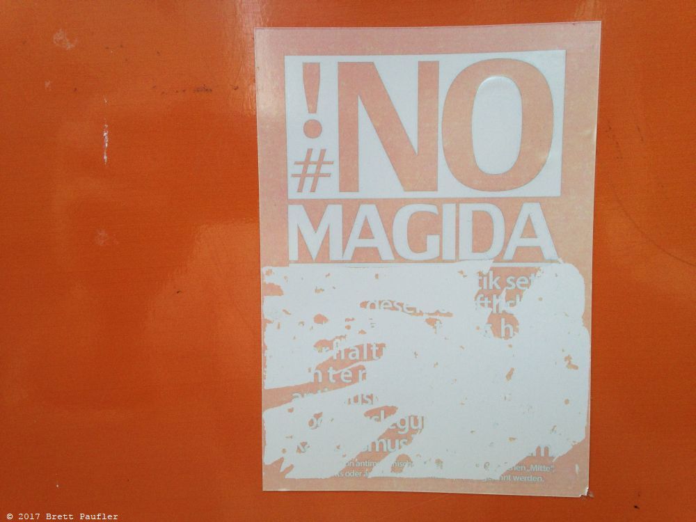 A random orange sticker that reads No Magida, who knows the full intent, the main text having been scraped away, still those words ring true, or their inverse
