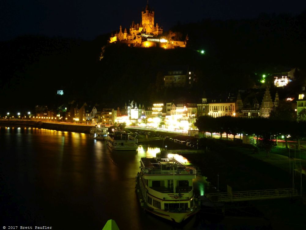 Castle lit up at night, view from a bridge, long exposure, lights illuminate the castle walls, a thing of beauty, and the boats on the river with lights of their own