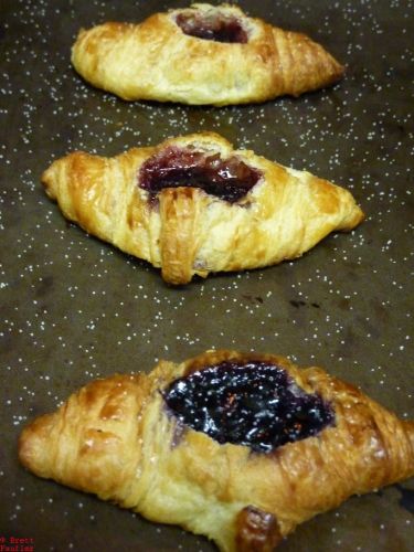 three croissants all in a row on the cookie sheet, jelly filled, with tons of salt sprinkled about