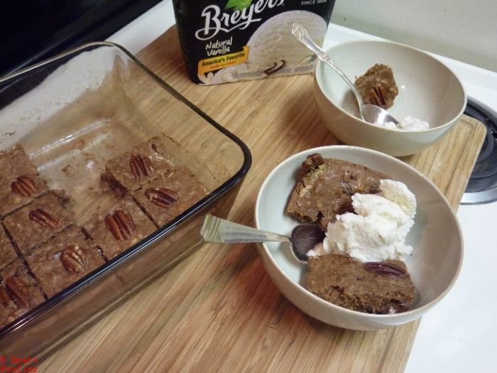 oatmeal cookie bars with pecans pressed into the squares to the side with a few pieces missing, ice cream carton in the back and two bowls of ice cream and oatmeal cookie bars, one has more than the other, have whichever you prefer, there's plenty more