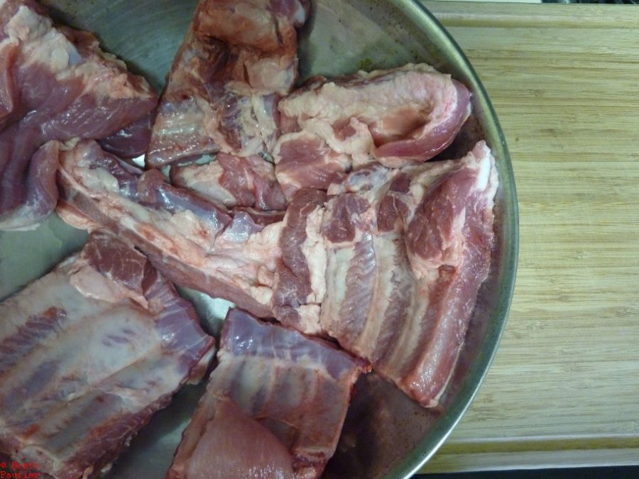 Raw Baby Back or more likely adult back ribs, spaced out, single layer, filling a large stainless steel bowl