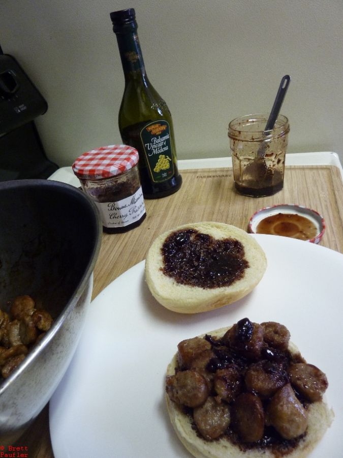 Sausage slices, cooked, on hamburger roll, with generous slather of barbecue vinegar jelly