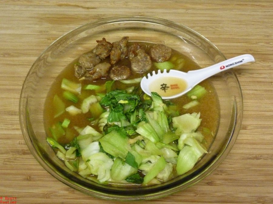 Looks like soup, good broth that sausage juice, bok choy with sausage in pie plate, clear, funky spoon I got as a promo for buying a case of ramen like noodles, and soup is one