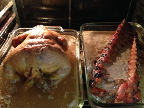 a whole chicken on the left and a rack of ribs on the right, cooking in the oven