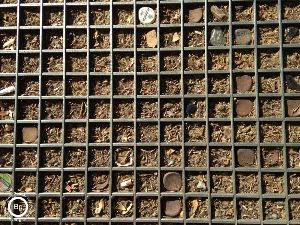 Coke bottle tops, and beer bottle tops, stuck into a grate, on the ground, it was one of those tree grates, used to protect a trees roots, that is landscaping bark in between, and a few of the grate areas have bottle tops, again, artsy image, knew it was a winner when I took it