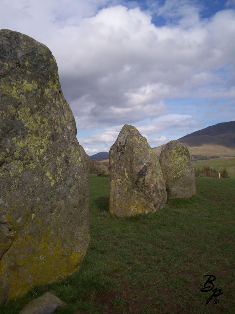 three vertical moss covered rocks, larger than a man, starting the arc of a circle, which one can see another of the number behind, between, and in back, once again, this is my only first hand experience with such stone circles and so forms the basis of such conjenctures