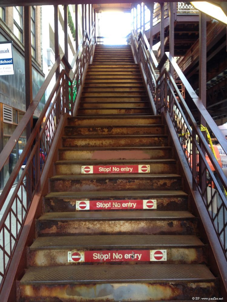 A photo of stairs leading up into the L, who knows the station, downtown Chicago, at the bottom, are do not enter signs and the like, I like the image, I like the glow of white at the top, and the rust on the metal stairs