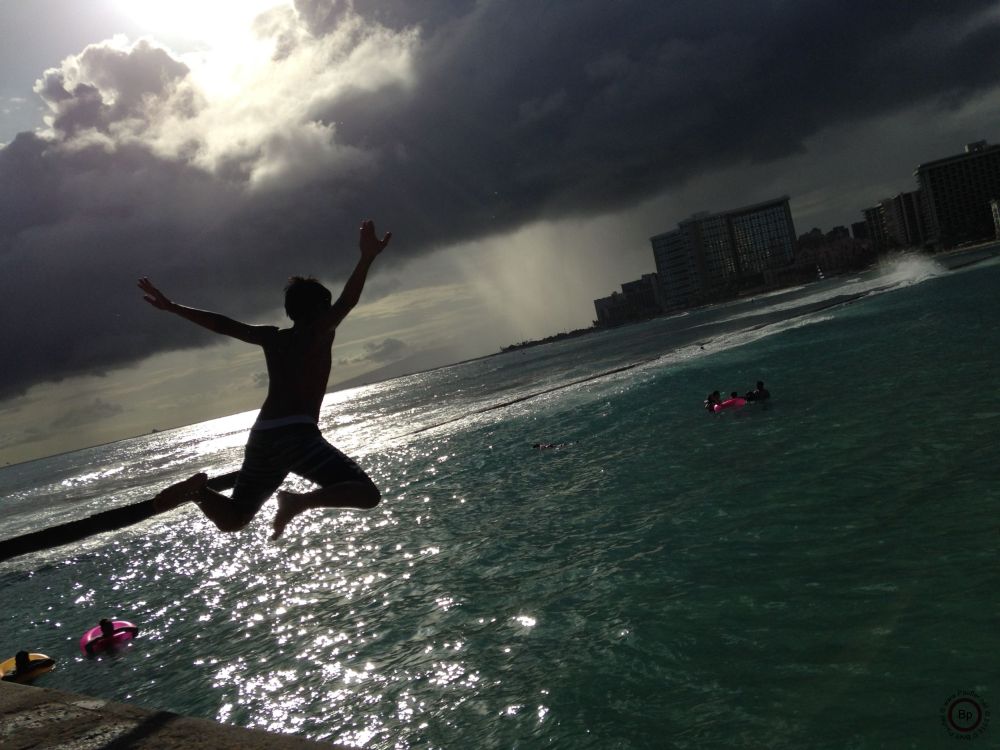 Child on pier jumping into ocean, looks like they are enjoying the fall