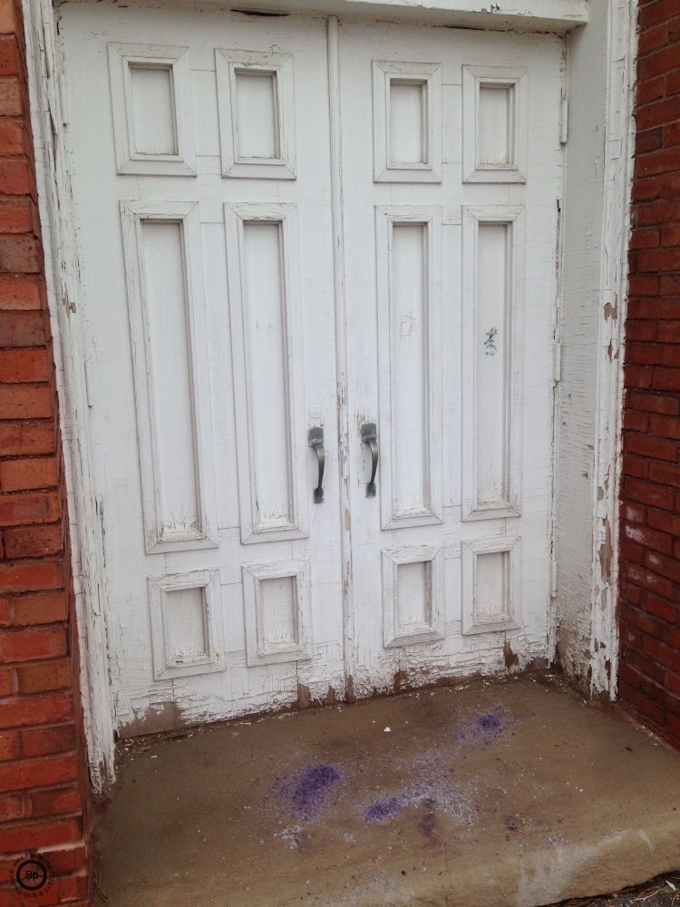 White door, fading paint, brick wall, purple crystals, which I assume to be salt, to melt snow, that is not yet present