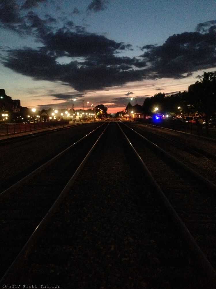 Train tracks heading out into the distance, the tracks were a common spot for my sunset pictures, as was the park down the way, no images from the park made the cut, two or three of the track ones were in the final cut, lights lining the way, sky turning to night, but it is the reflection of the light off the darkened tracks in the foreground that make the shot, the blue to the side is probably a police car, they did not spot me... not that there would have been cause, but just saying