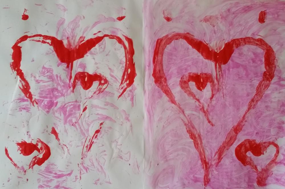 A finger painted heart on the right, folded over to make the impression on the left, two hearts, from one