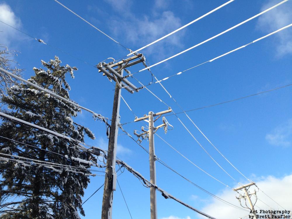 It is a nice clear sky, looking up we see power lines, covered in a thick layer of ice, maybe an inch on the wires, it is very nice looking, very pleasing to the ice, and something not seen all that terribly often