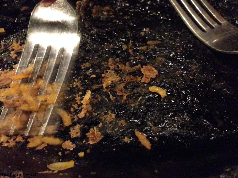 The scraped clean cast iron fajita plate being dragged over by a fork, getting that last little bit of crispy rice