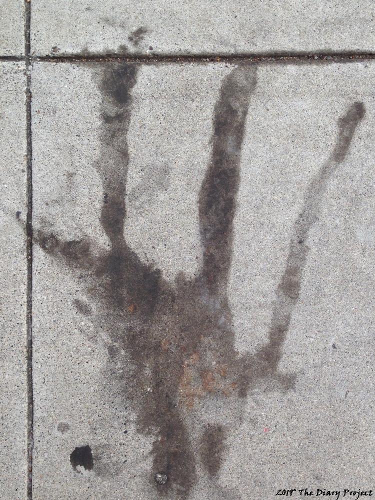 This image was not taken in a Cemetery, maybe not even the same state, stain on concrete, which looks sort of like a hand to me
