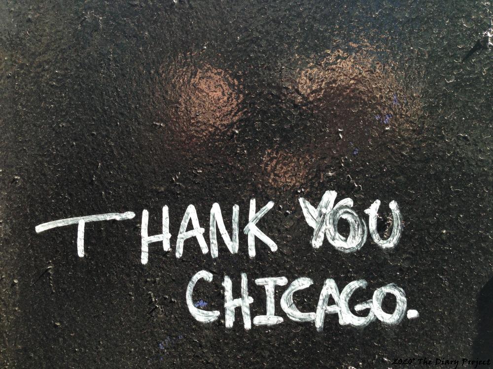 White marker paint on a glassy black background topped by three pinkish splotches of reflected light, this is graffiti, which reads... Thank You Chicago