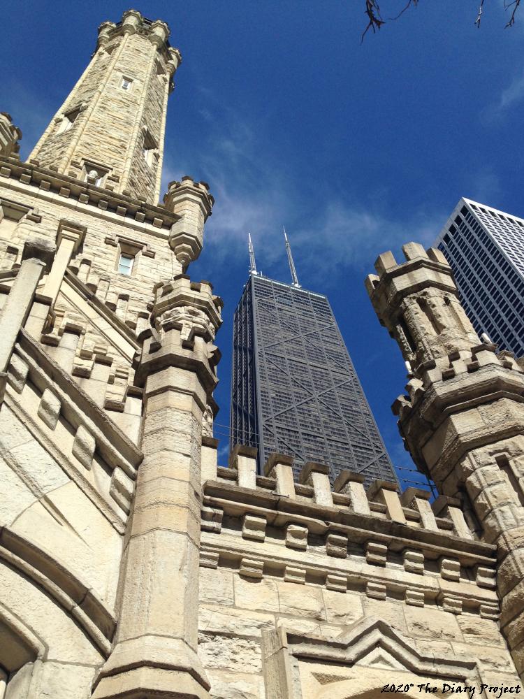 The old and the new, The Hancock Building, or what used to be called The Hancock Building, standing behind the water tower, peaking between two towers, a nice blue sky, so a stone buidling in the foreground and a glass steel tower in the background, I was downtown on the day that follows, but nowhere near this local, in fact, this image is from almost a year ago